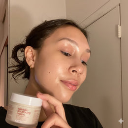 Person holding a jar of 'seedskid' resurfacing cream in front of their face.